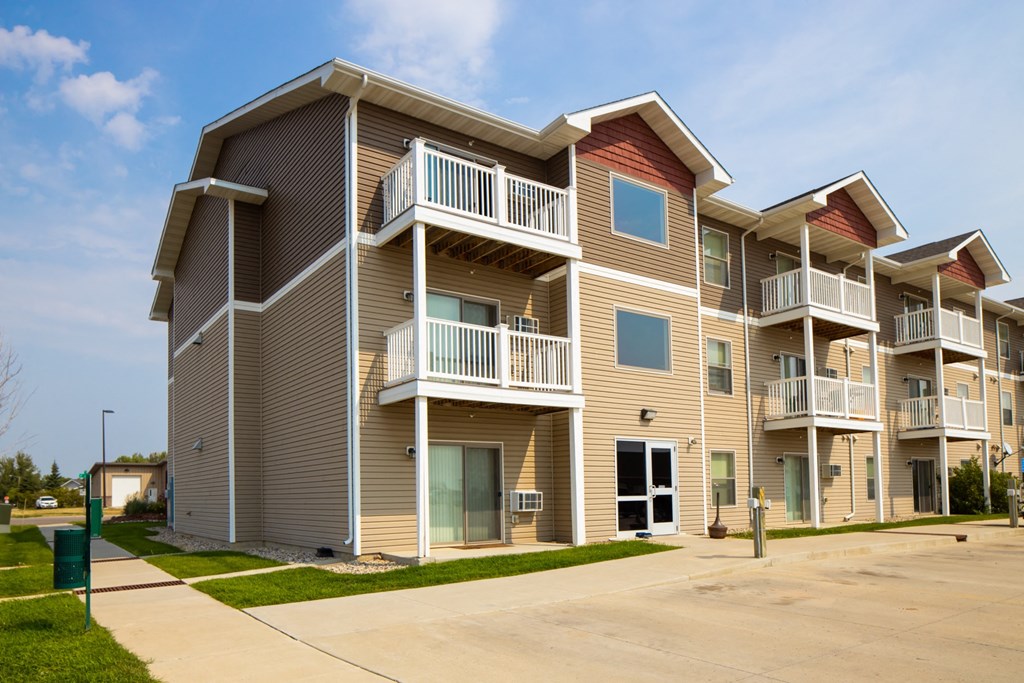 the exterior of an apartment building with balconies and a sidewalk