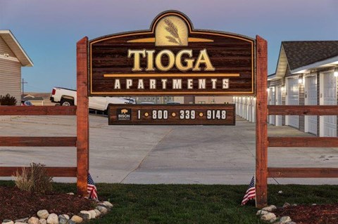 a sign for toga apartments in front of a driveway