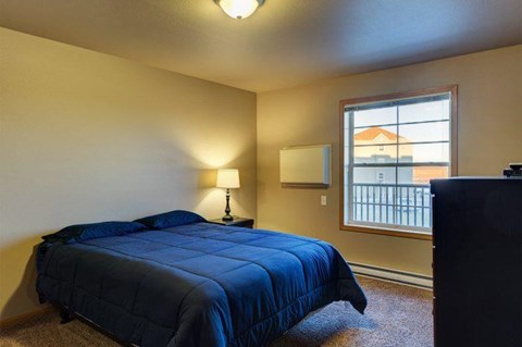 A bedroom with a bed, lamp, and window.