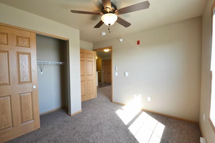 a living room with a ceiling fan and a closet