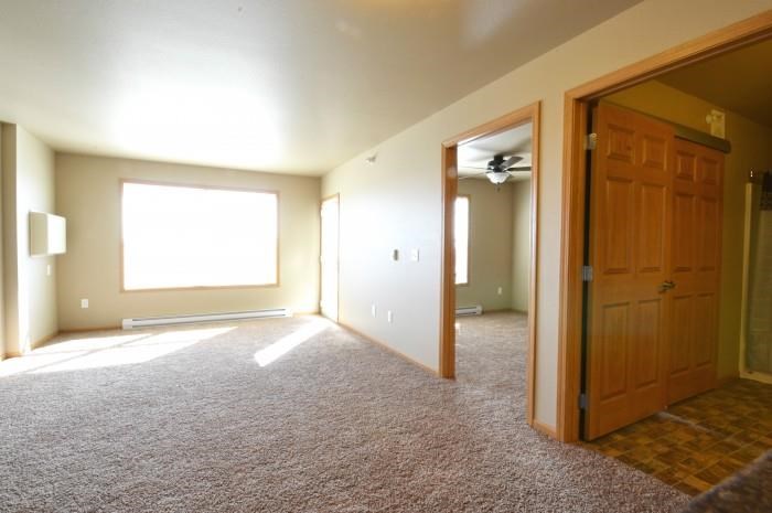 an empty living room with a door and a window