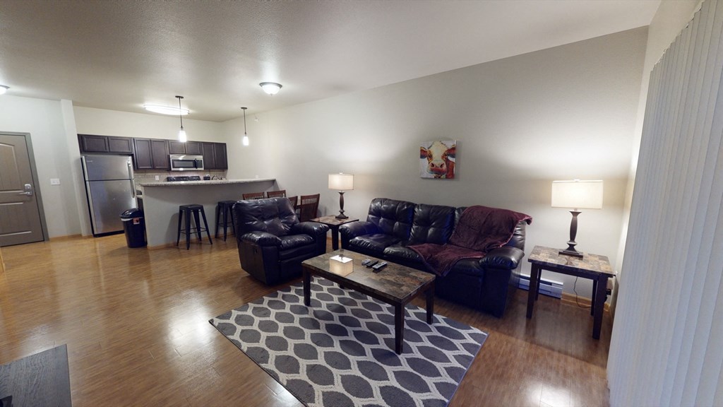 an open living room with leather furniture and a kitchen