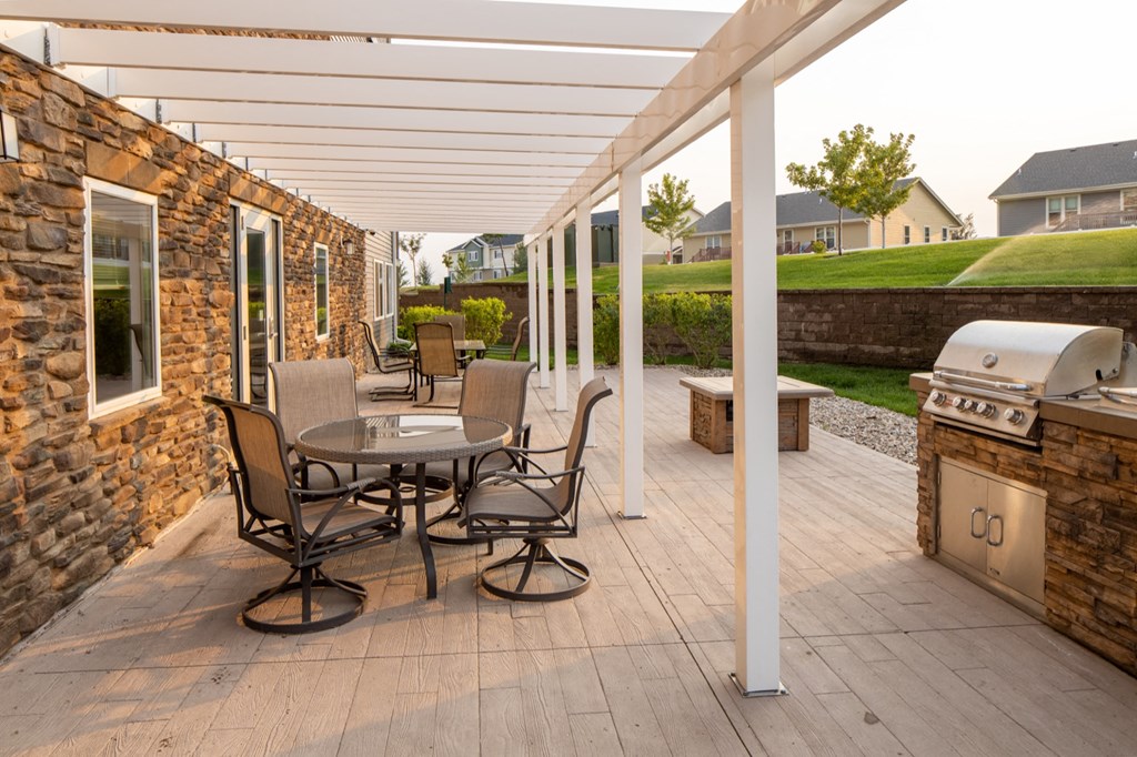 a patio with a table and chairs and a grill