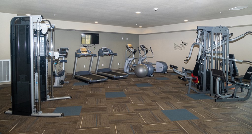 a gym with cardio equipment and weights on a wooden floor