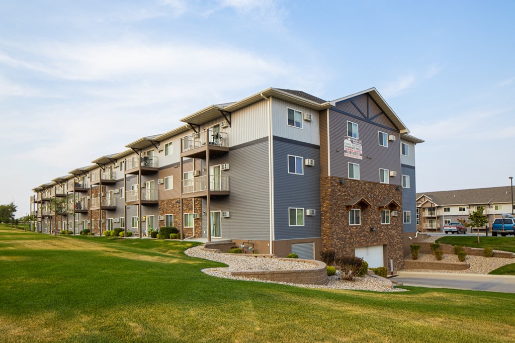 an exterior view of an apartment building with a green lawn
