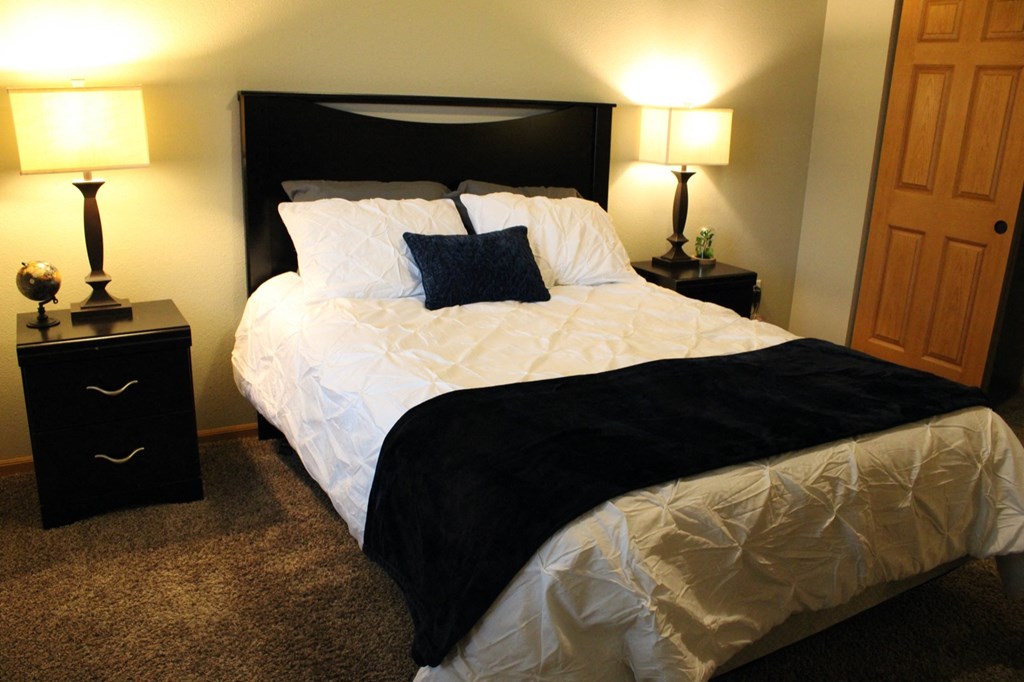 a bedroom with a bed and two lamps and a closet