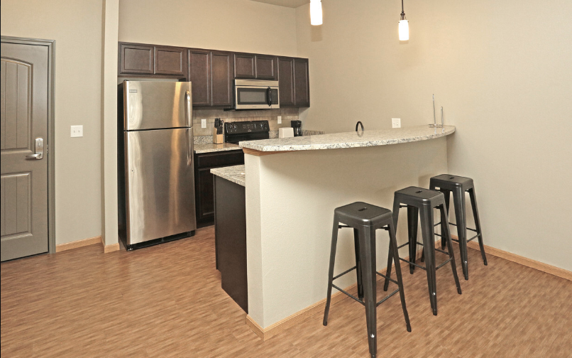 a kitchen with a bar and a stainless steel refrigerator