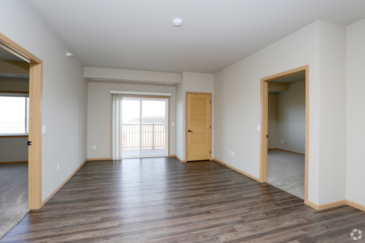 an empty living room with wood floors and a door to a balcony