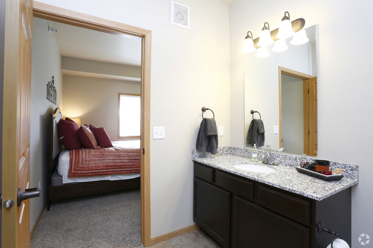a bathroom with a sink and a mirror and a bedroom with a bed