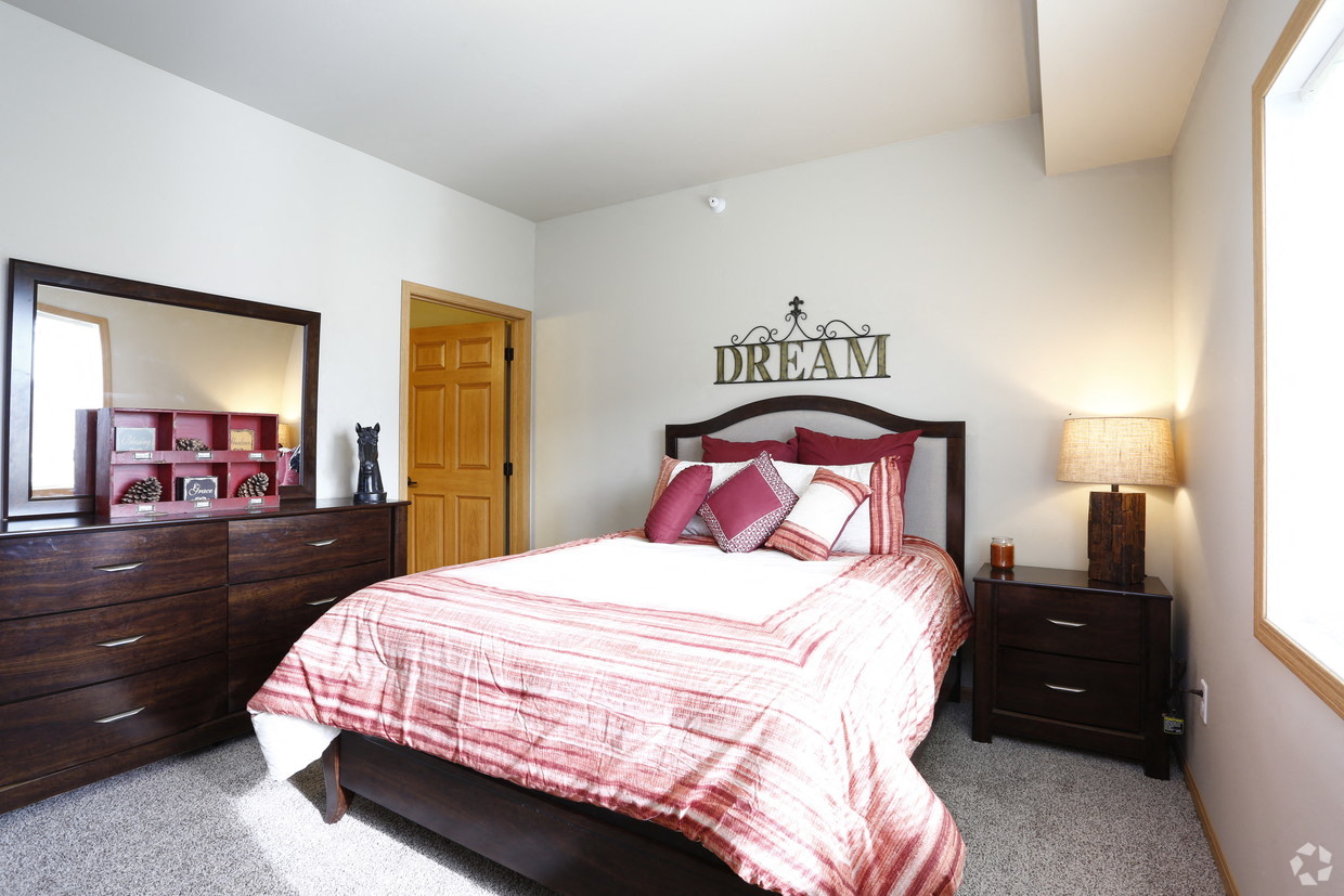 a bedroom with a bed and two dressers and a mirror