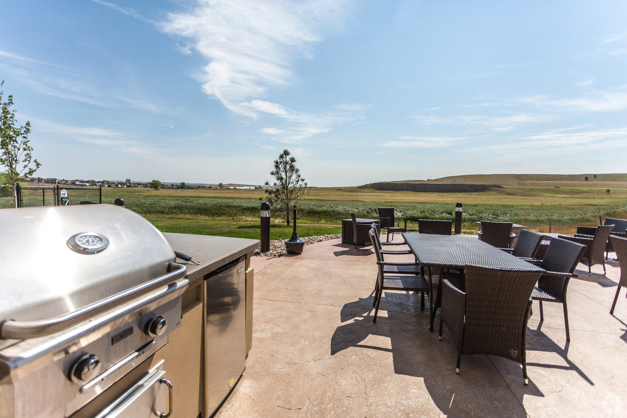 a patio with a grill and a table with chairs