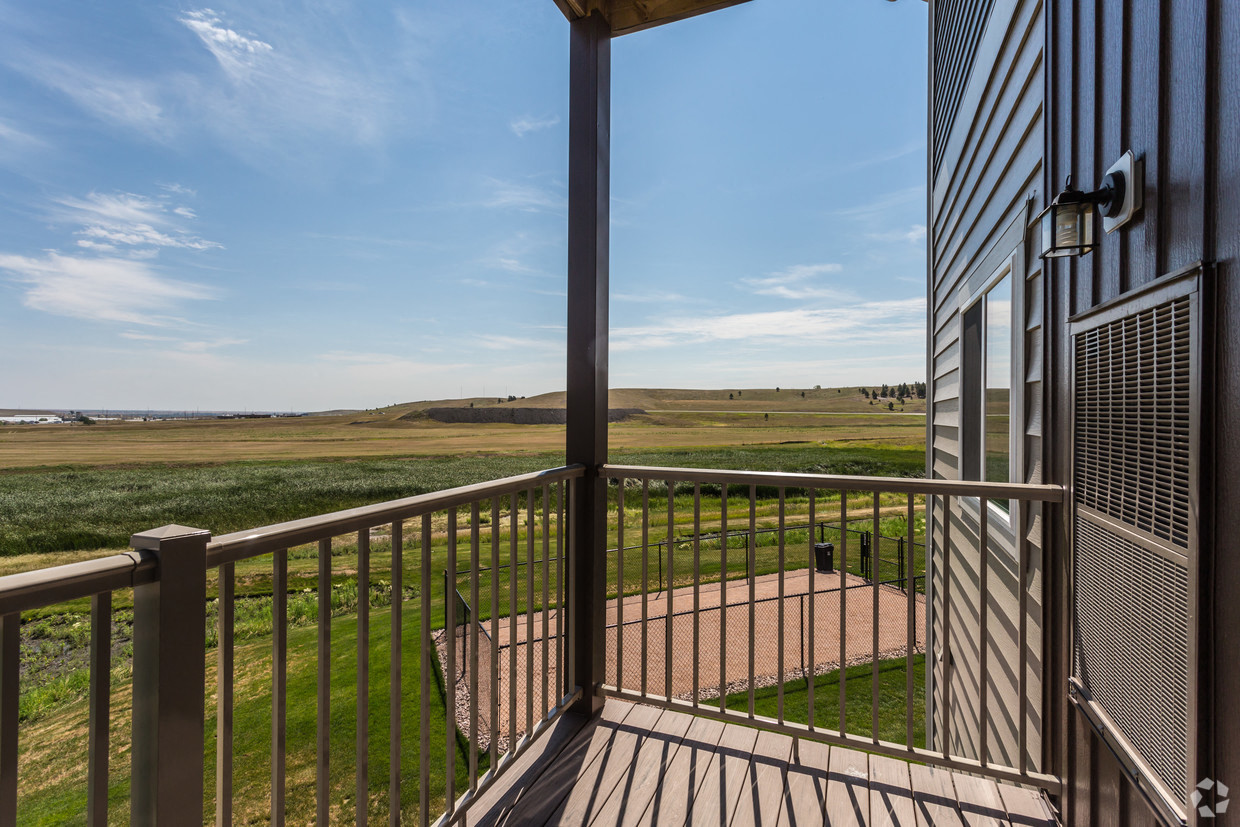 a balcony with a view of a field and a blue sky