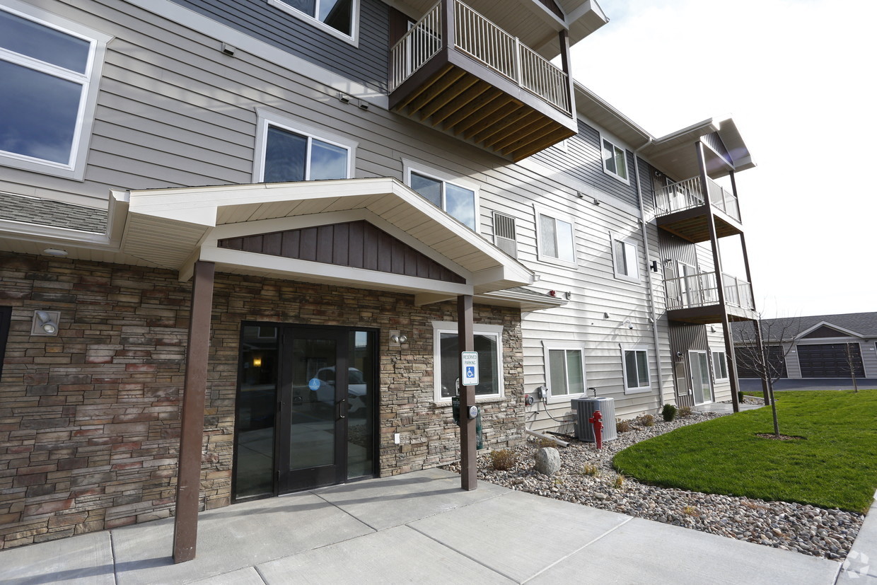 the front of an apartment building with a driveway and a balcony