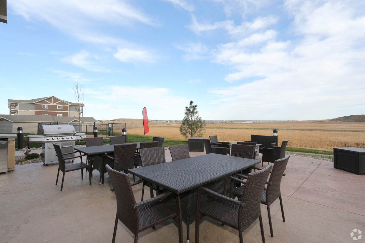 a patio with tables and chairs and a view of a field