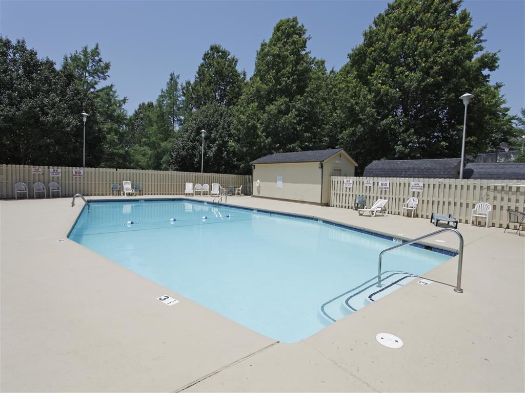a swimming pool with chairs around it and trees in the background