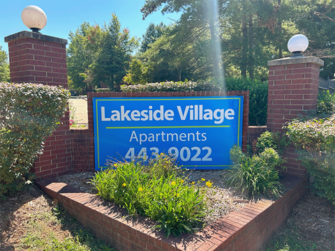 a sign for lakeside village apartments in front of a garden