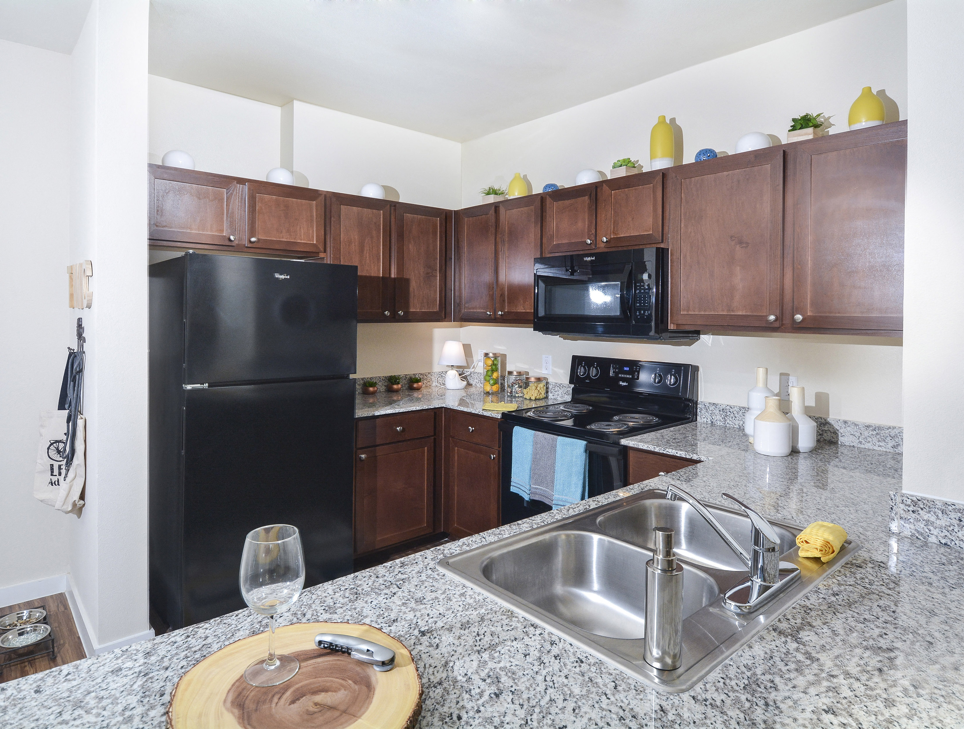 A kitchen with a black refrigerator and a granite counter top.