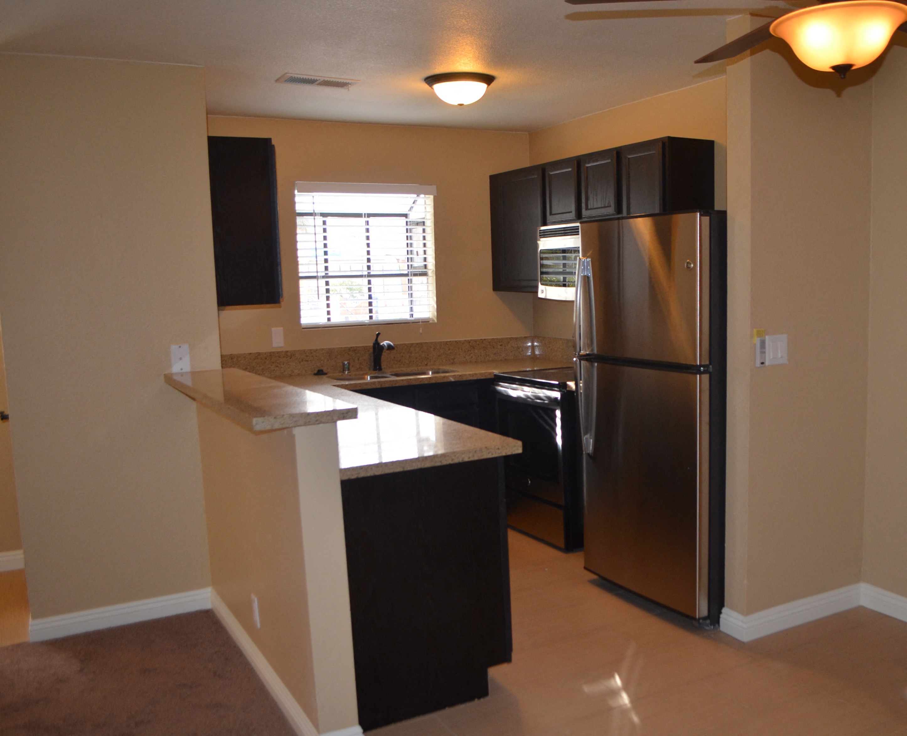 A kitchen with a refrigerator, sink, and cabinets.