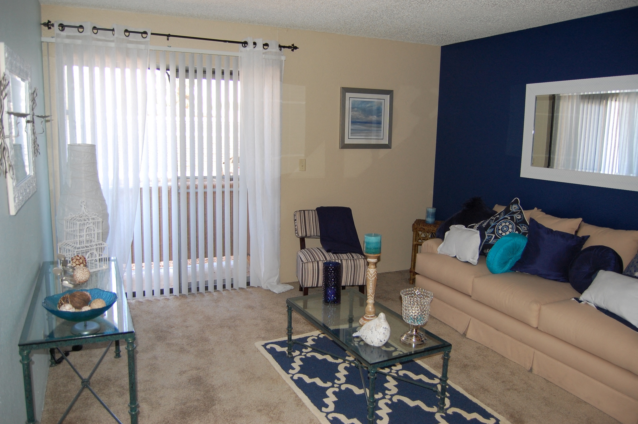 A living room with a glass coffee table and a striped chair.