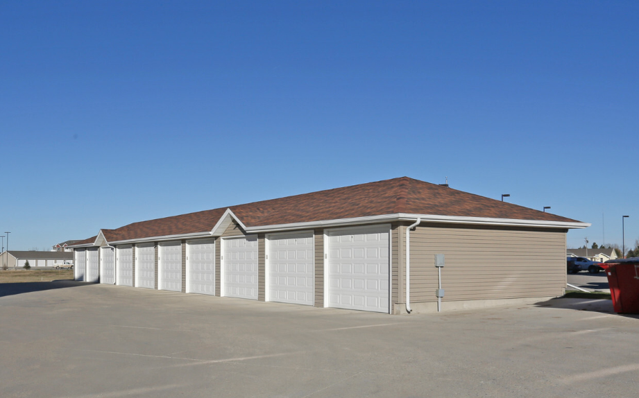 a row of garages in a parking lot with a blue sky