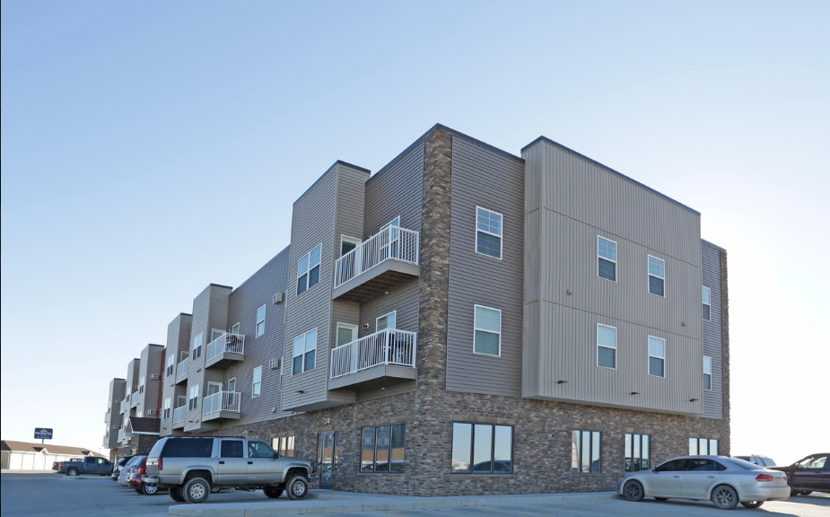 an apartment building with cars parked in front of it
