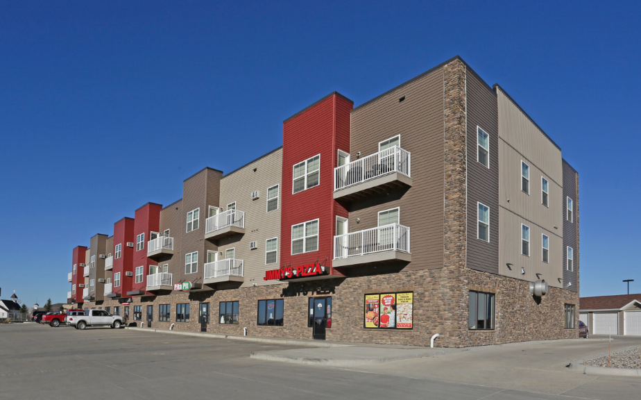 a row of apartment buildings with balconies and a parking lot