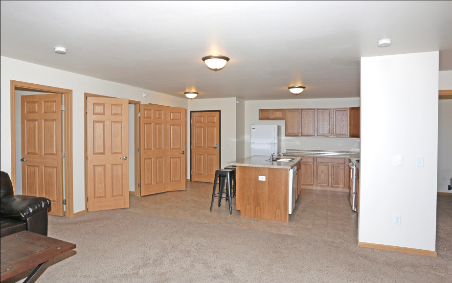 an empty living room with a kitchen and a bar