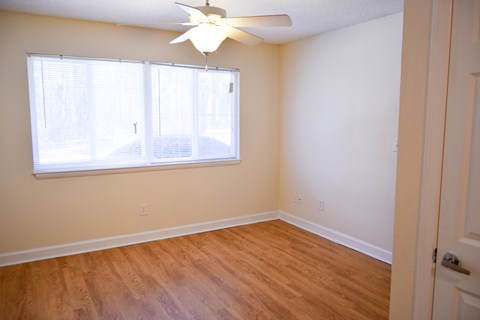 an empty bedroom with a large window and a ceiling fan