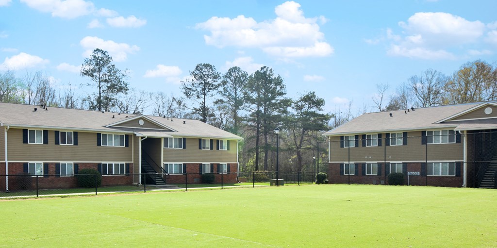 two apartment buildings on a lush green field