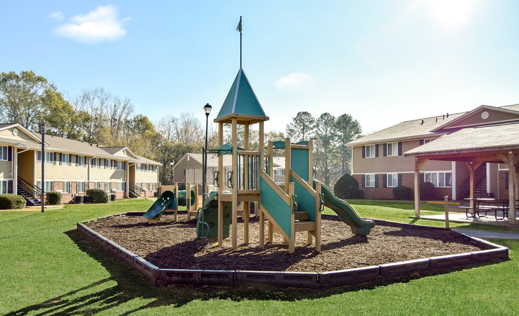a playground with slides and a tower in front of houses