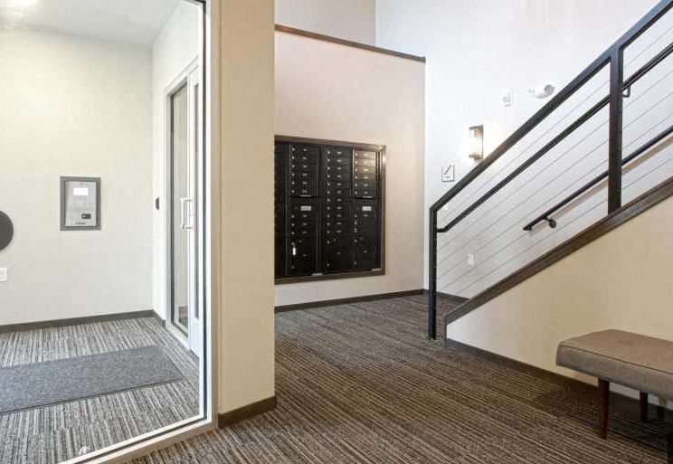 a hallway with a staircase and a door and a mirror