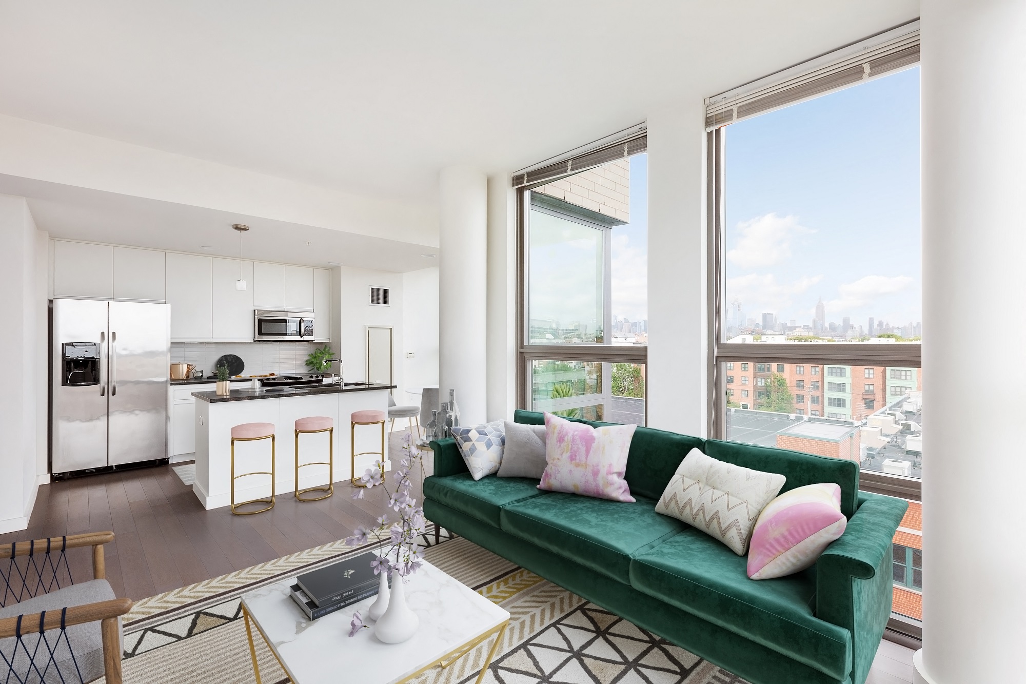 A modern living room with a green couch and a kitchen area in the background.