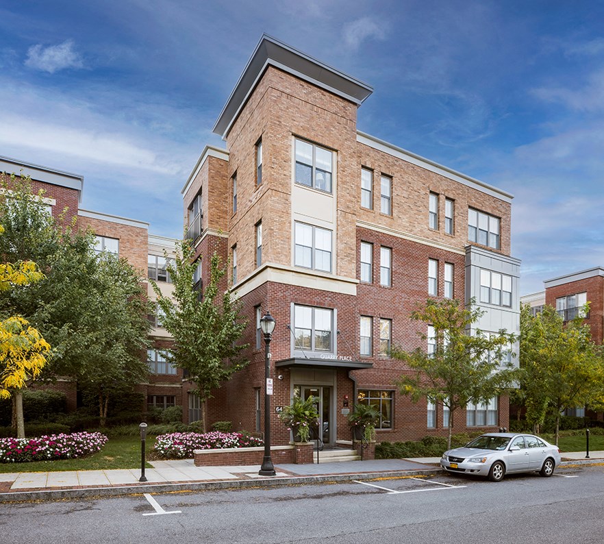 a brick apartment building on a city street with a car