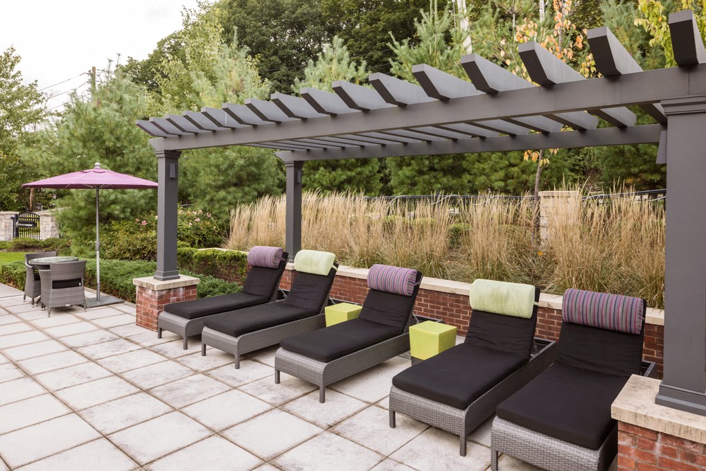 a group of lounge chairs under a pergola on a patio