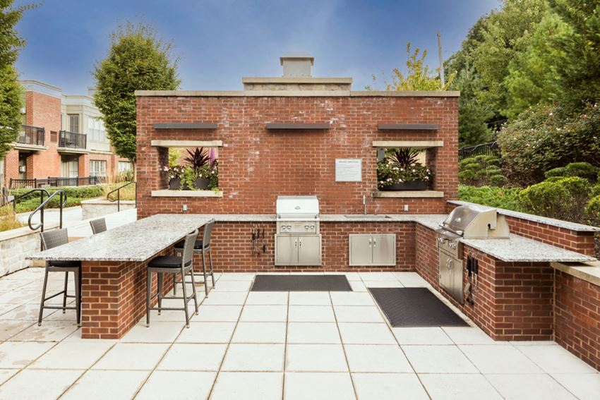the outdoor kitchen has a bar and a counter top with stainless steel appliances