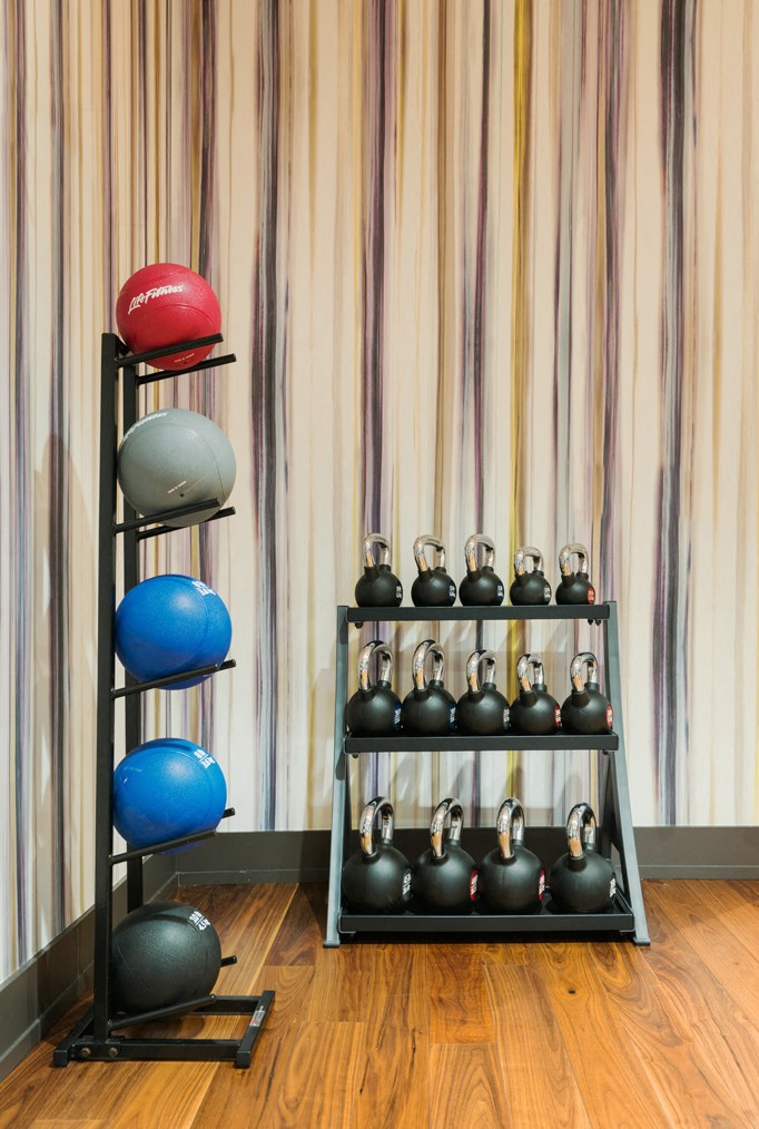 a rack of dumbbells on a wooden floor next to a wall with curtains