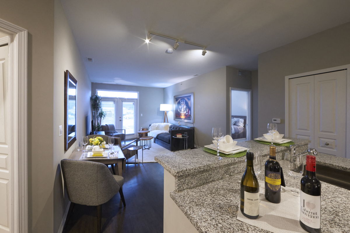 a living room with a bar with bottles of wine on it