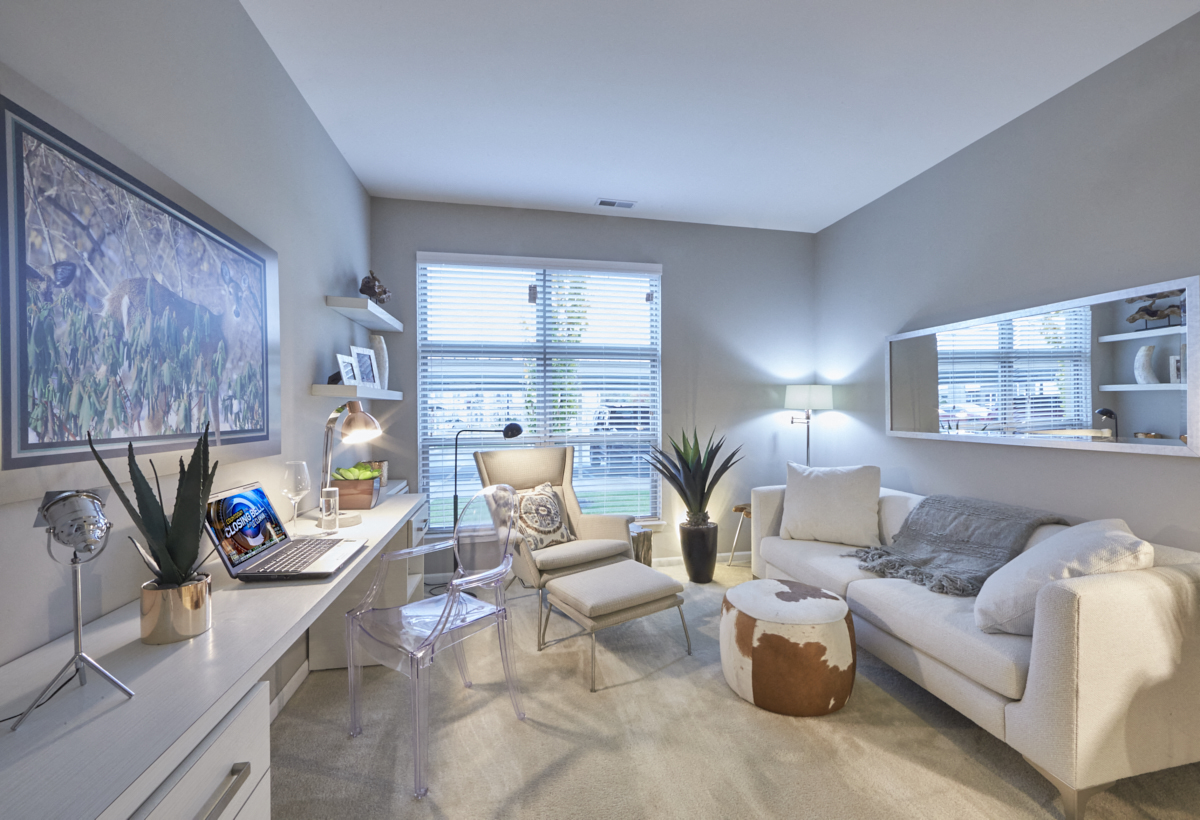 a living room with a couch and a desk with a laptop