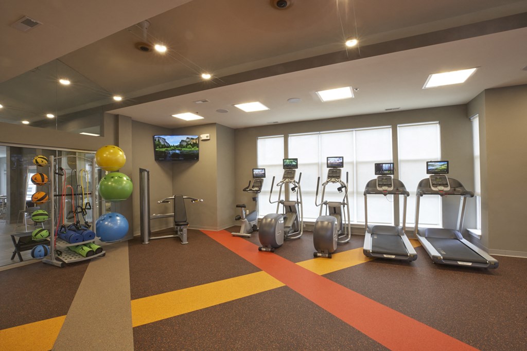 a gym with treadmills and other exercise equipment in a room with windows