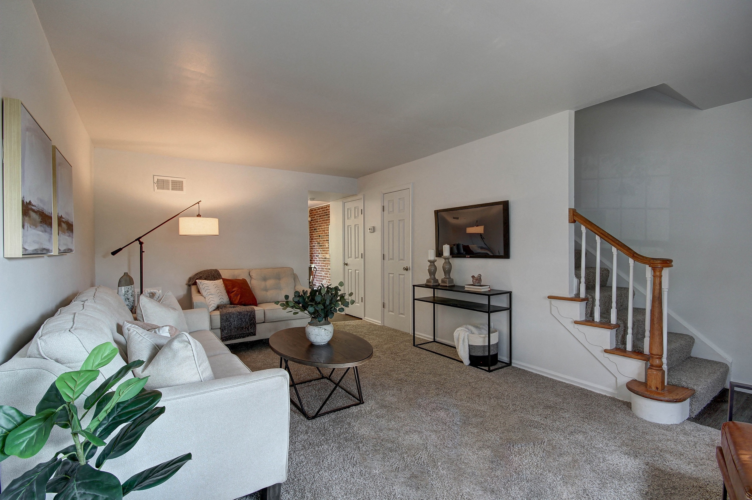 a living room with a white couch and a staircase