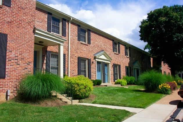 a brick apartment building with a sidewalk and grass