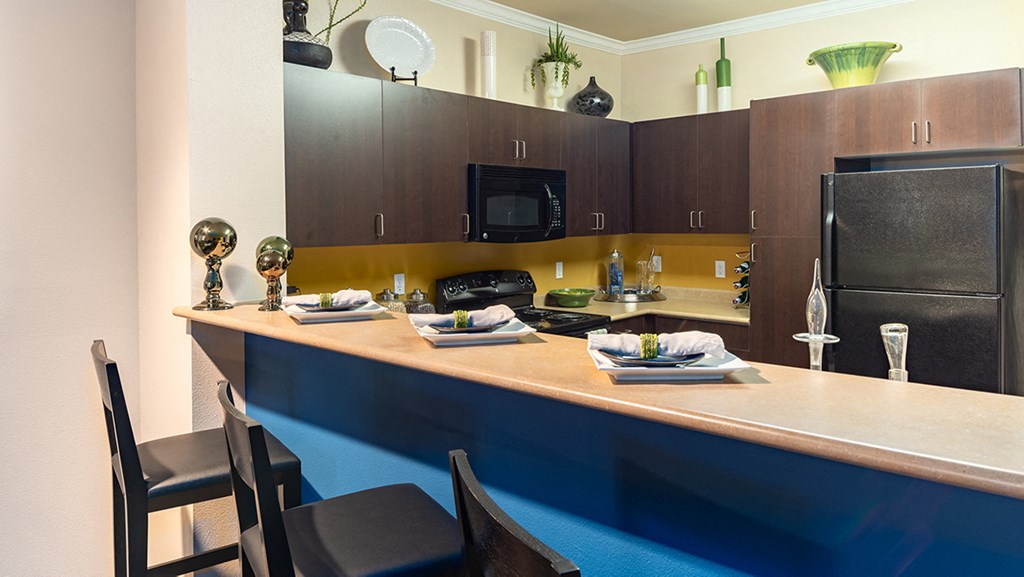 a kitchen with a long counter top and a stainless steel refrigerator