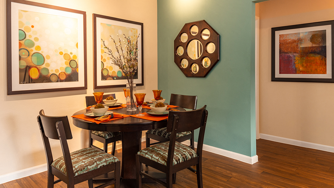 a dining room with a table and chairs and paintings on the wall