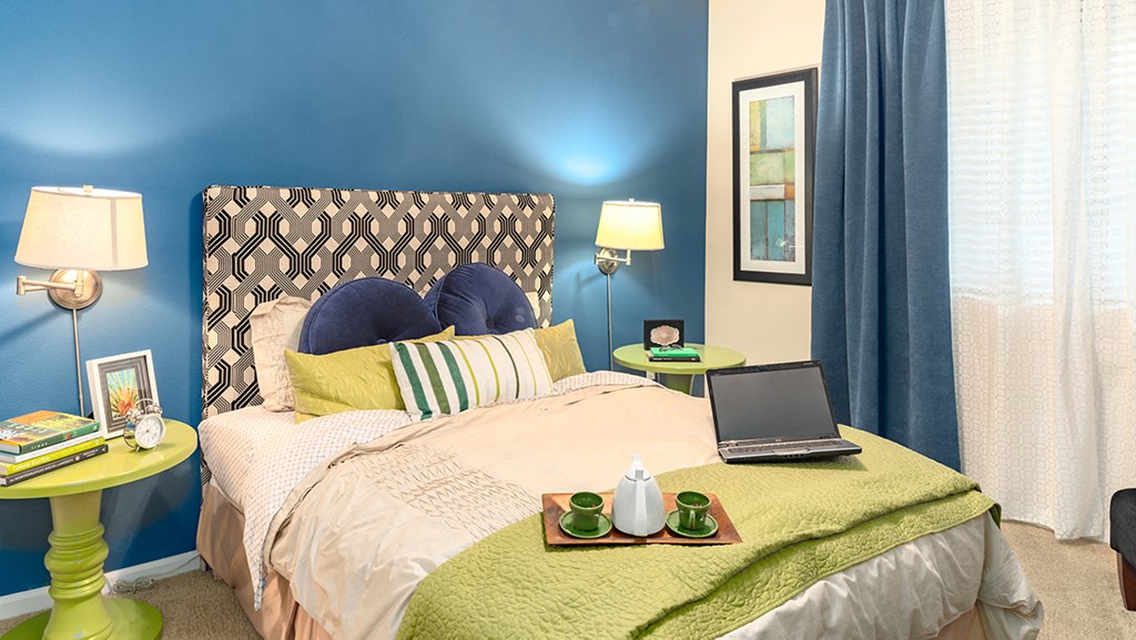 a bedroom with blue walls and a bed with a laptop on it