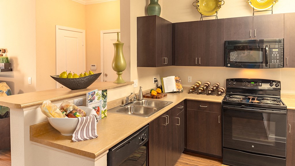 a kitchen with dark cabinets and a bowl of fruit on the counter