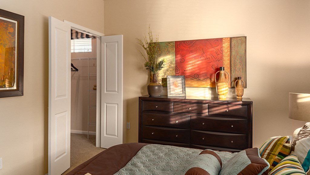 a bedroom with a large bed and a dresser with a plant on top of it