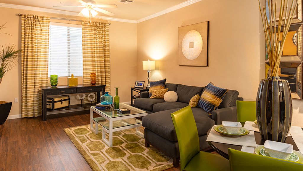a living room with a brown couch and green chairs