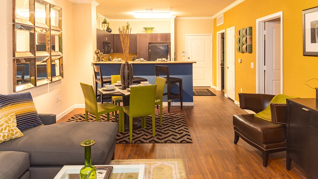 a living room and dining room with a kitchen in the background