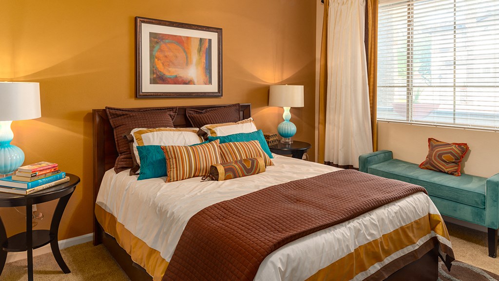 a bedroom with a bed and a chair in front of a window
