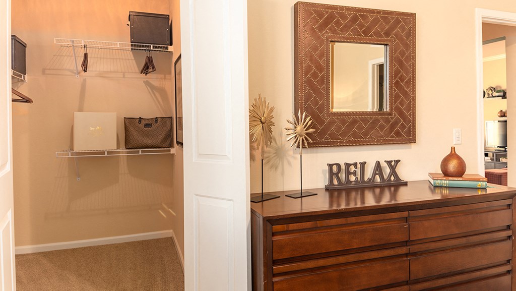 a walk in closet with a dresser and mirror